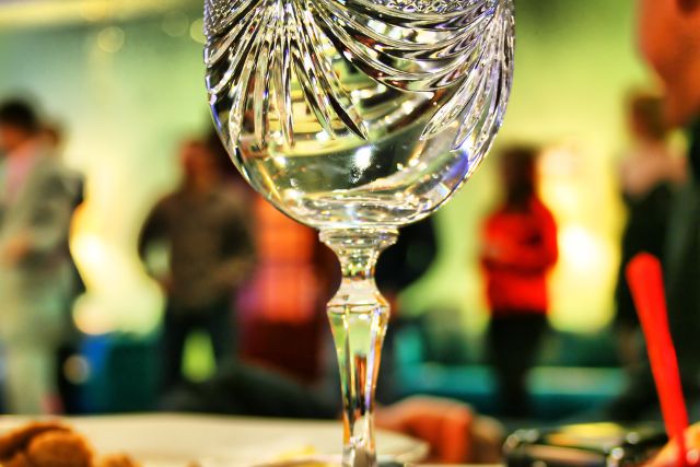 An upclose photo of a crystal goblet in an evening party background.