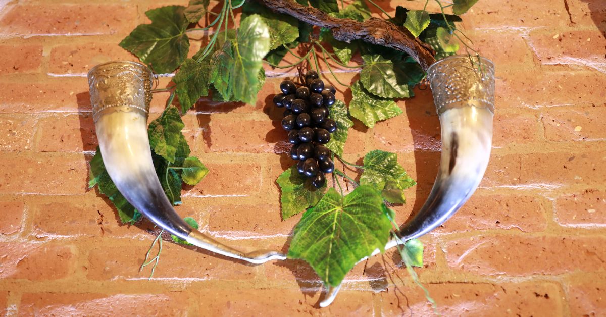 Twho drinking horns hanged and displayed in a brivk wall.