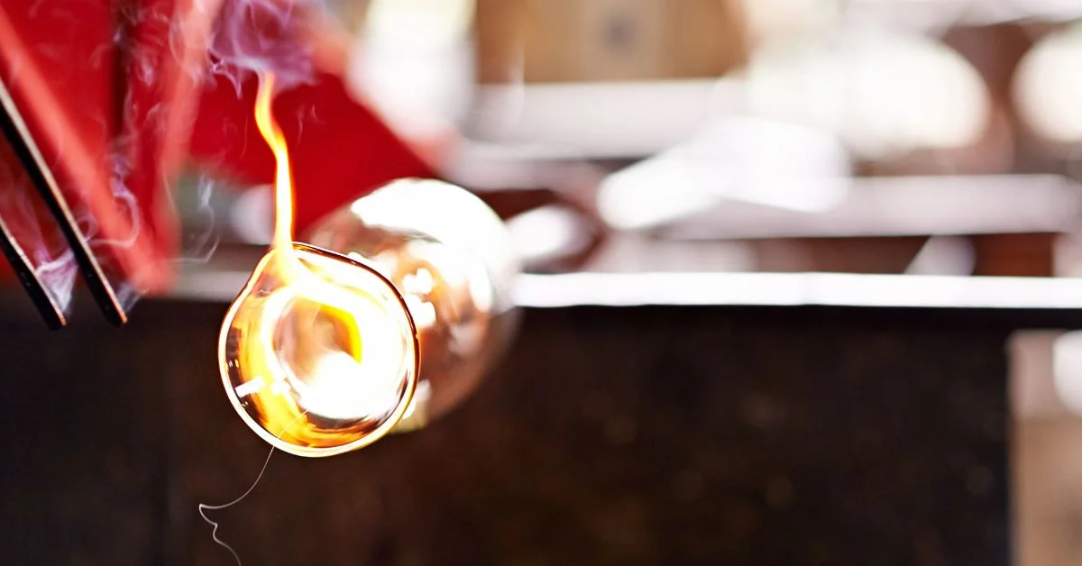 A raw glass being shaped using a glassblower.