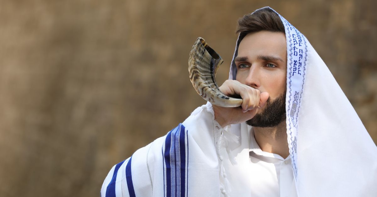 Jewish man using a blowing horn know as shofar.