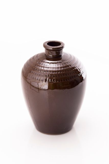 Close-up photo of a brown porcelain flagon in white background.
